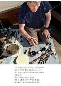 a man is sitting on a blanket and playing a musical instrument