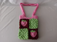 a pink and green crocheted bag with strawberries on it