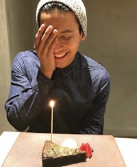 a man is holding a piece of cake with a candle in it