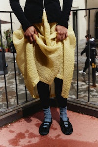 a person wearing a yellow skirt and black shoes