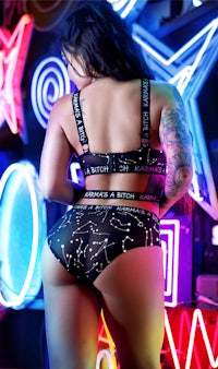a woman in black lingerie posing in front of neon signs