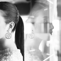 a black and white photo of a woman wearing earrings
