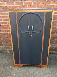 a black and wood cabinet in front of a brick wall