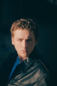 a young man in a leather jacket is posing for a photo