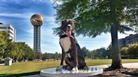 a dog sits on a pedestal in front of a tower