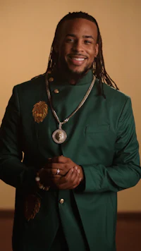 a man in a green suit with dreadlocks smiling