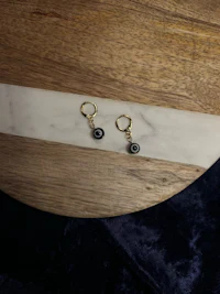 black evil eye hoop earrings on a wooden table