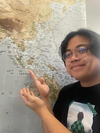 a young man pointing to a map of the world