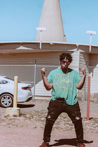 a man in a green shirt is standing in front of a building
