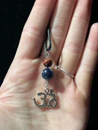 a person holding a necklace with an om symbol on it