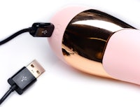 a pink and gold vibrator is connected to a usb cable