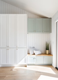 a room with white cabinets and a bench