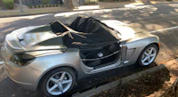 a silver sports car with its door open on the side of the road