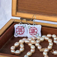 embroidered earrings and pearls in a wooden box