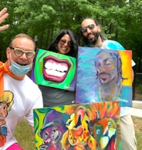 a group of people posing for a photo with their paintings