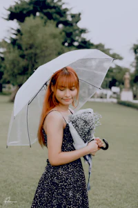 a girl with red hair holding an umbrella in a park