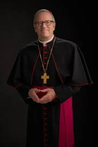 a priest in a black and red robe posing for a photo