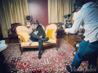 a man in a hat sitting on a couch with a camera