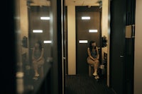 a woman sitting in a hallway with a mirror in front of her