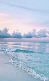 a beach with waves and clouds at sunset