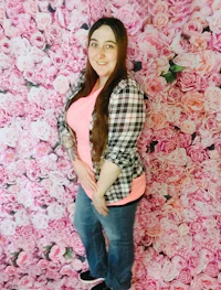 a woman posing in front of a pink flower wall