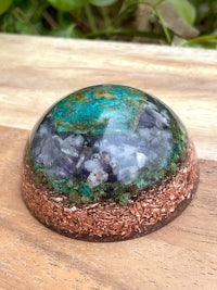 a turquoise and copper sphere on top of a wooden table
