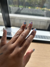 a person's hand holding a glass of water in front of a window