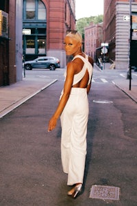 a woman in a white jumpsuit walking down the street