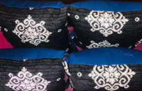four black and blue pillows on a pink bed