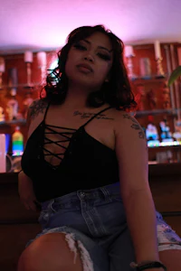 a woman wearing a black tank top and denim shorts