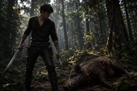 a man with a sword in the woods next to a dead pig