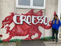 a girl standing in front of a wall with a dragon painted on it