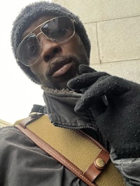 a man wearing a hat, gloves and sunglasses