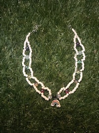 a necklace with a rainbow on it laying on the grass