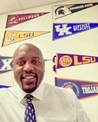 a man in a tie standing in front of a wall full of pennants
