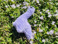 a purple stuffed animal laying in the grass