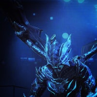 a man in a blue costume standing in front of a blue light