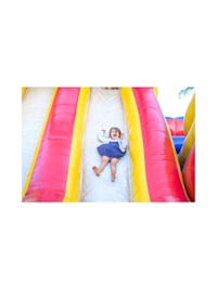a little girl laying down on a large inflatable slide