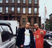 two men standing next to each other in front of a building