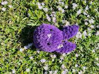 a purple stuffed animal is laying in the grass