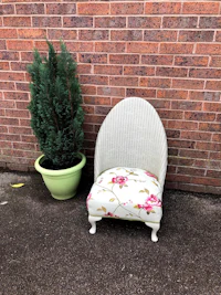 a white chair with a flower pot in front of a brick wall