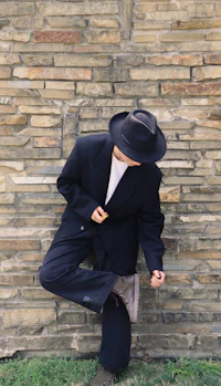 a man in a suit leaning against a brick wall