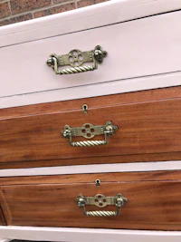 a pink and white dresser with brass handles