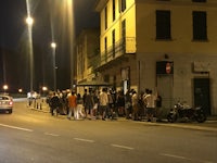 a group of people standing on the side of a street at night