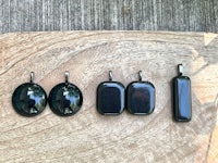 a set of black glass earrings on a wooden cutting board