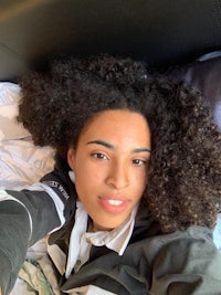 a young woman laying on a bed with curly hair