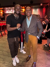 two men standing next to each other in a room