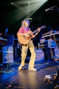 a woman playing an acoustic guitar on stage