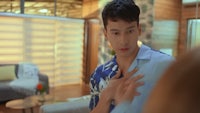 a man in a hawaiian shirt is looking at his chest