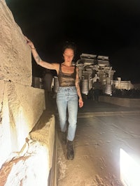 a woman standing on a stone wall at night